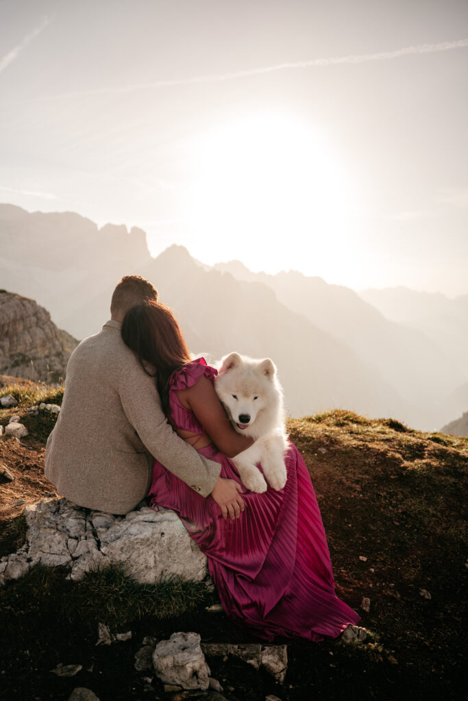 Couple with dog watching mountain sunset