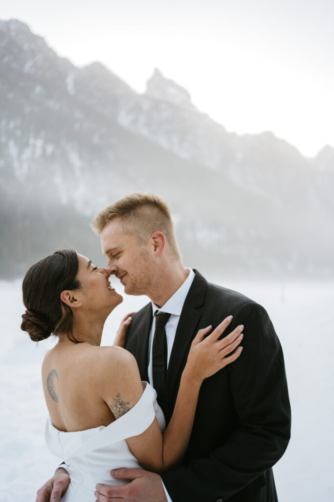 Couple embraces in front of snowy mountain landscape.