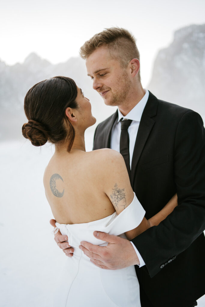 Bride and groom embracing in snowy mountains