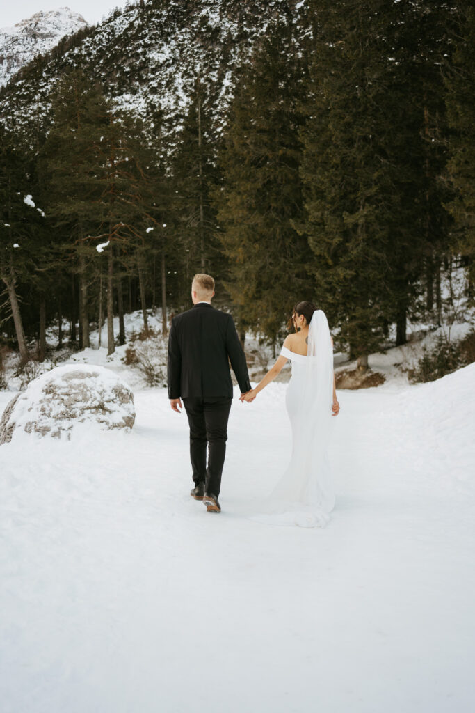 Bride and groom walking in snowy forest