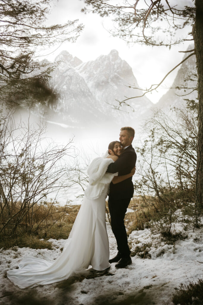 Bride and groom hugging in snowy mountains