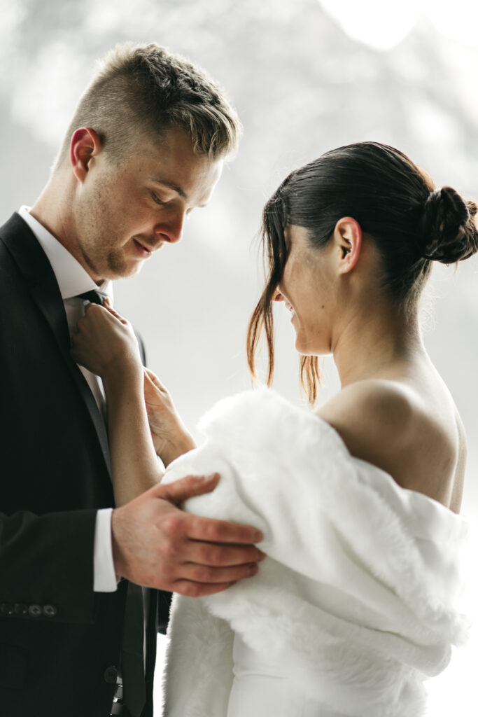 Bride adjusts groom's tie before wedding ceremony.