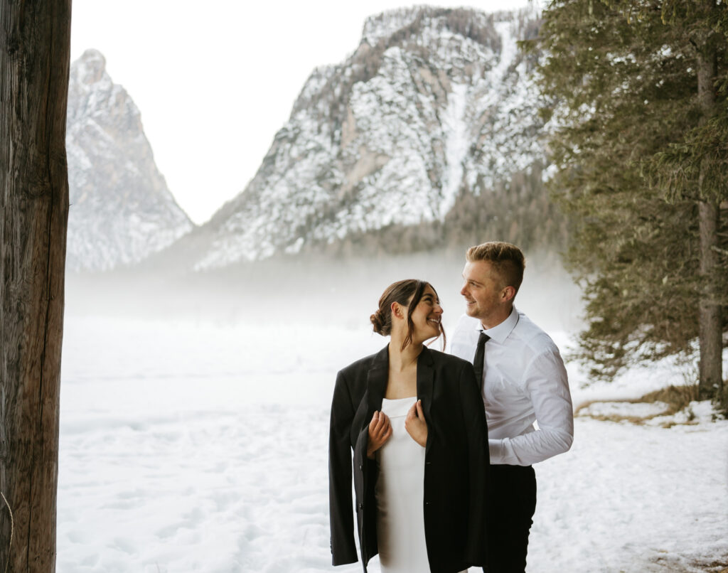 Couple smiling in snowy mountain landscape.