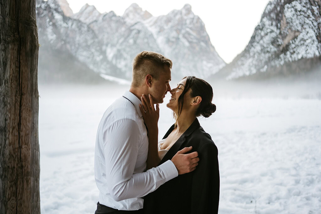 Couple embracing in a snowy mountain landscape.