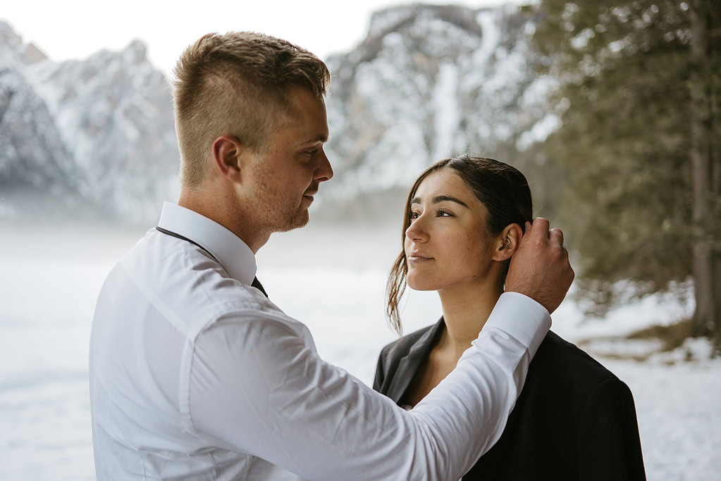 Couple embraces in snowy forest landscape.