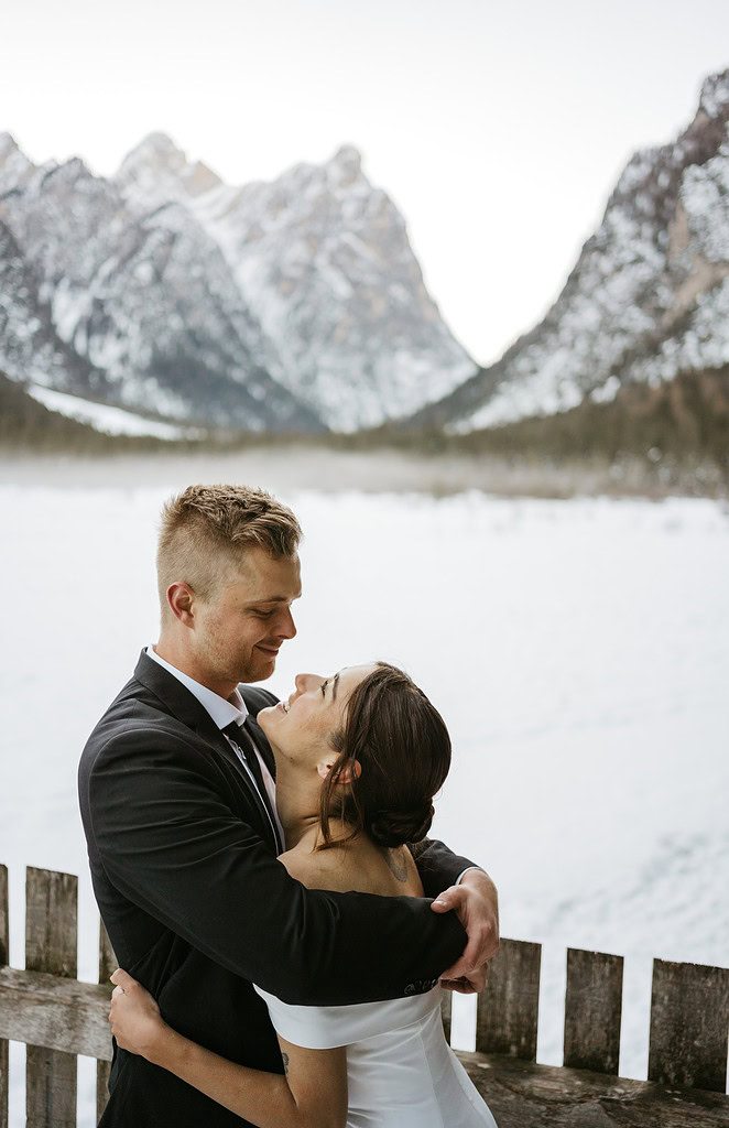 Couple embraces in snowy mountain landscape wedding scene.