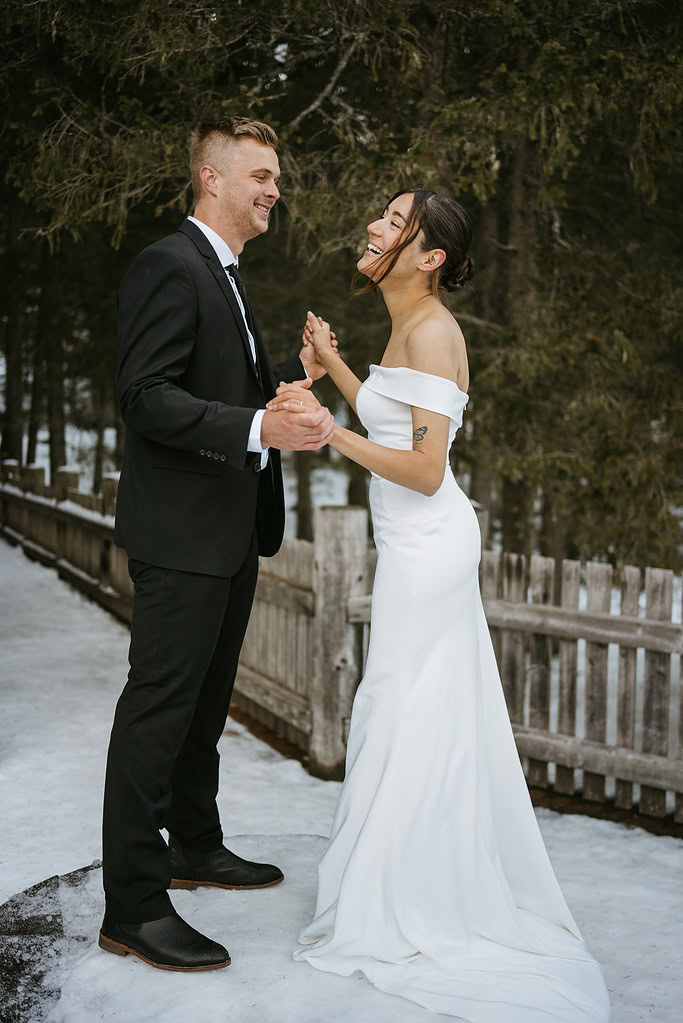 Couple dancing in snow, wedding attire, happy moment.