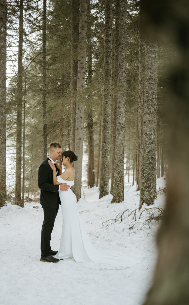 Bride and groom in snowy forest embrace