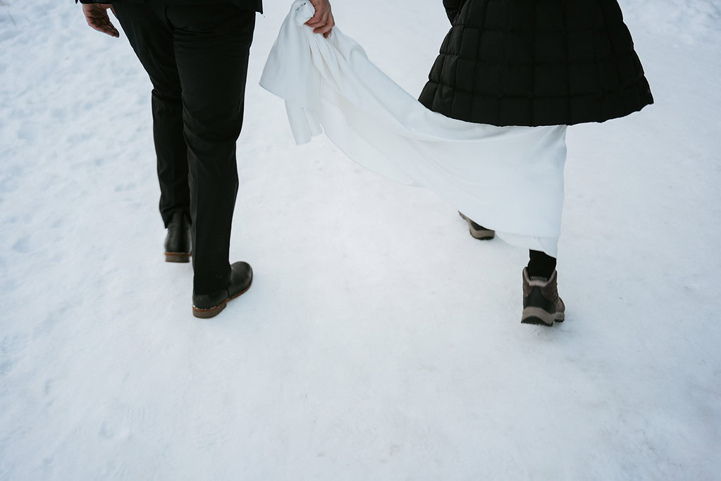 Couple walking on snowy path in winter clothing.