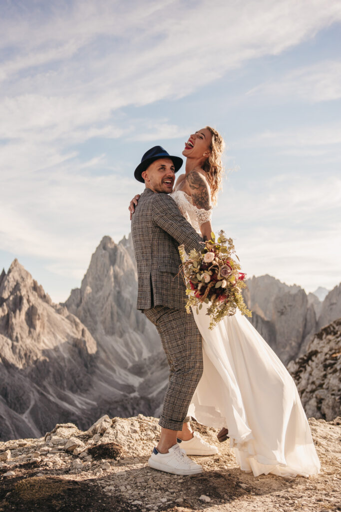 Couple embracing on mountain in wedding attire