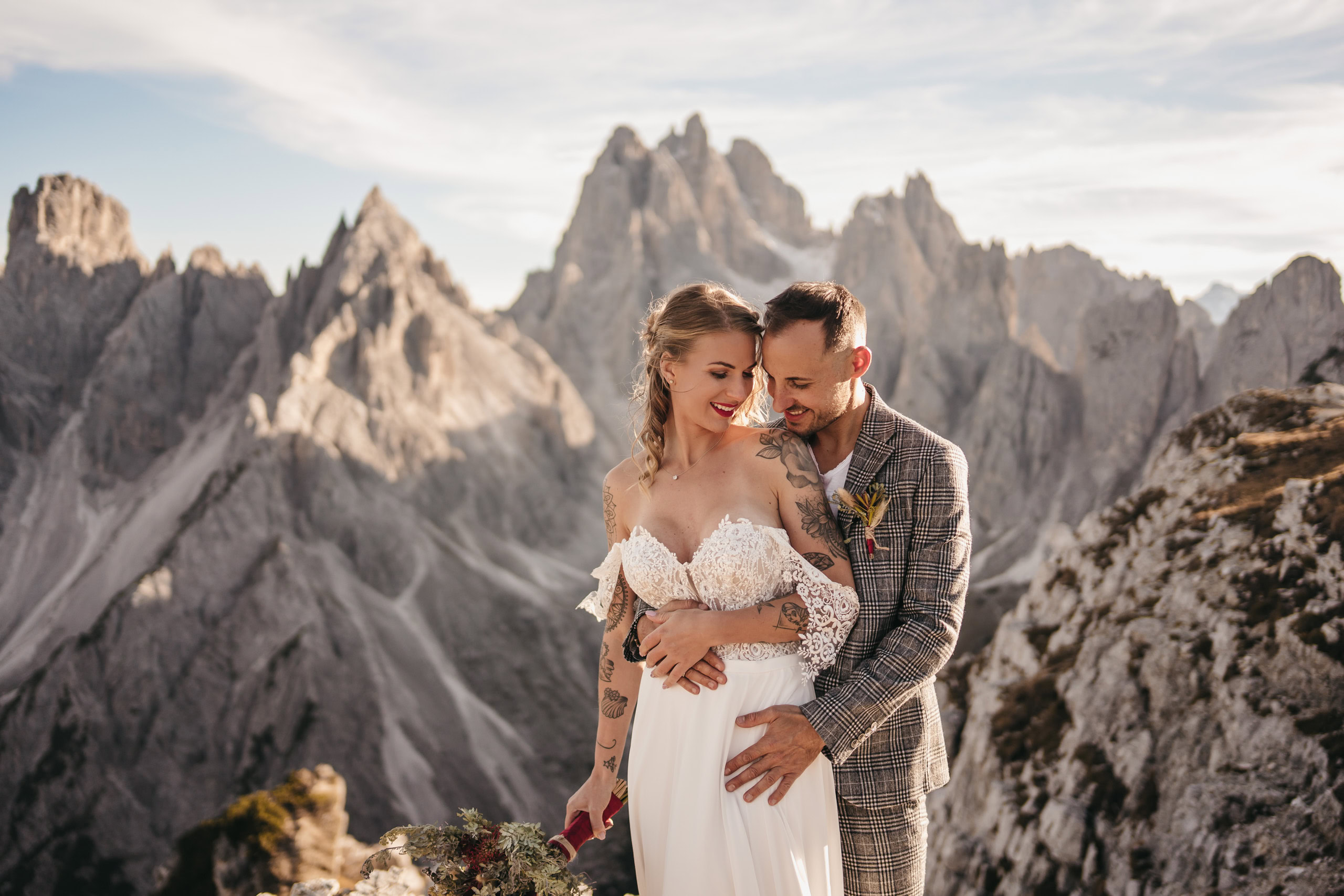 Bride and groom embracing in mountain setting.