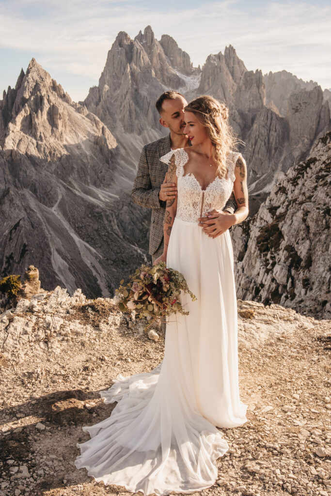 Wedding couple embraces on mountain cliff