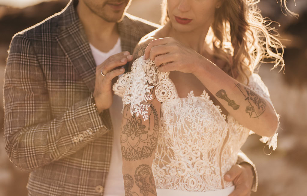 Couple adjusting lace wedding dress outdoors