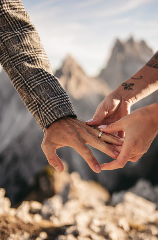 Close-up of a couple exchanging wedding rings outdoors.