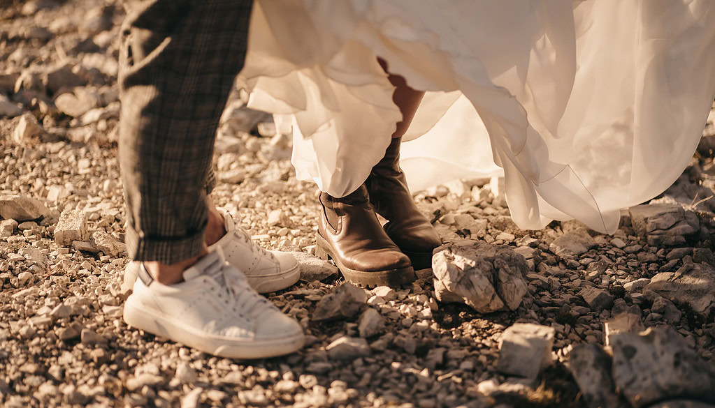 Bride in boots, groom in sneakers on rocky ground