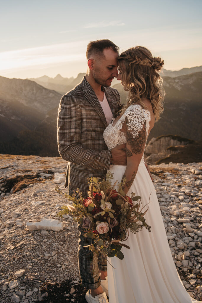 Bride and groom embrace in mountain sunset.