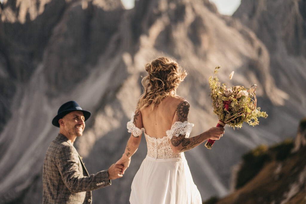 Couple in wedding attire in mountain scenery.