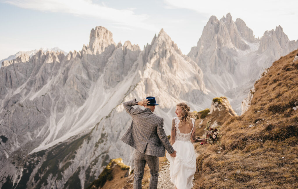 Couple hiking in wedding attire near mountains