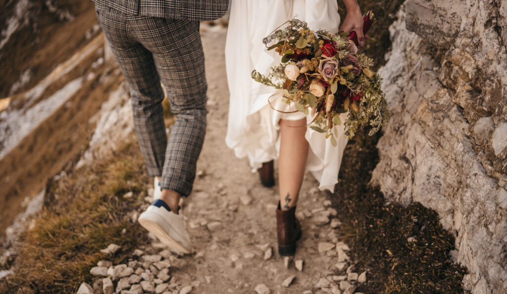 Couple walking on rocky trail with bouquet