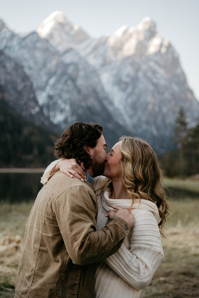 Couple kissing in front of snowy mountains