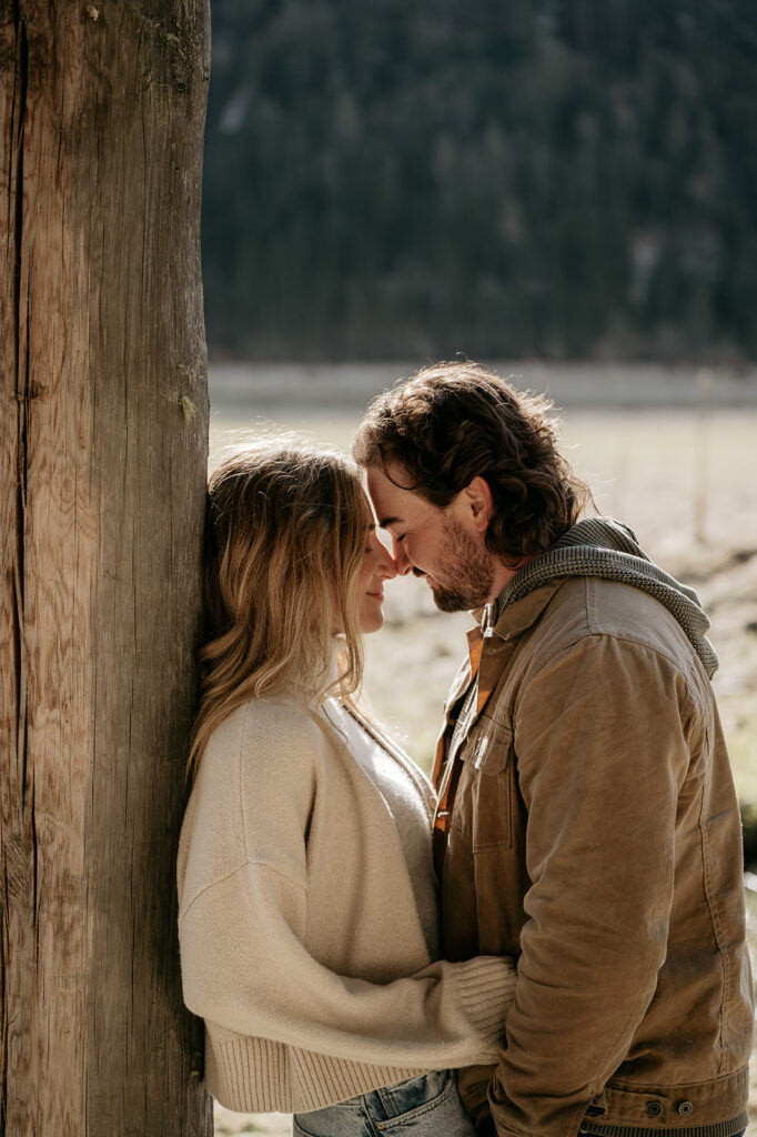 Couple embracing near wooden pillar outdoors.