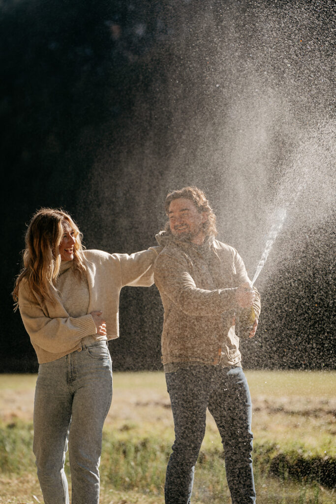 Couple celebrating with champagne outdoors.