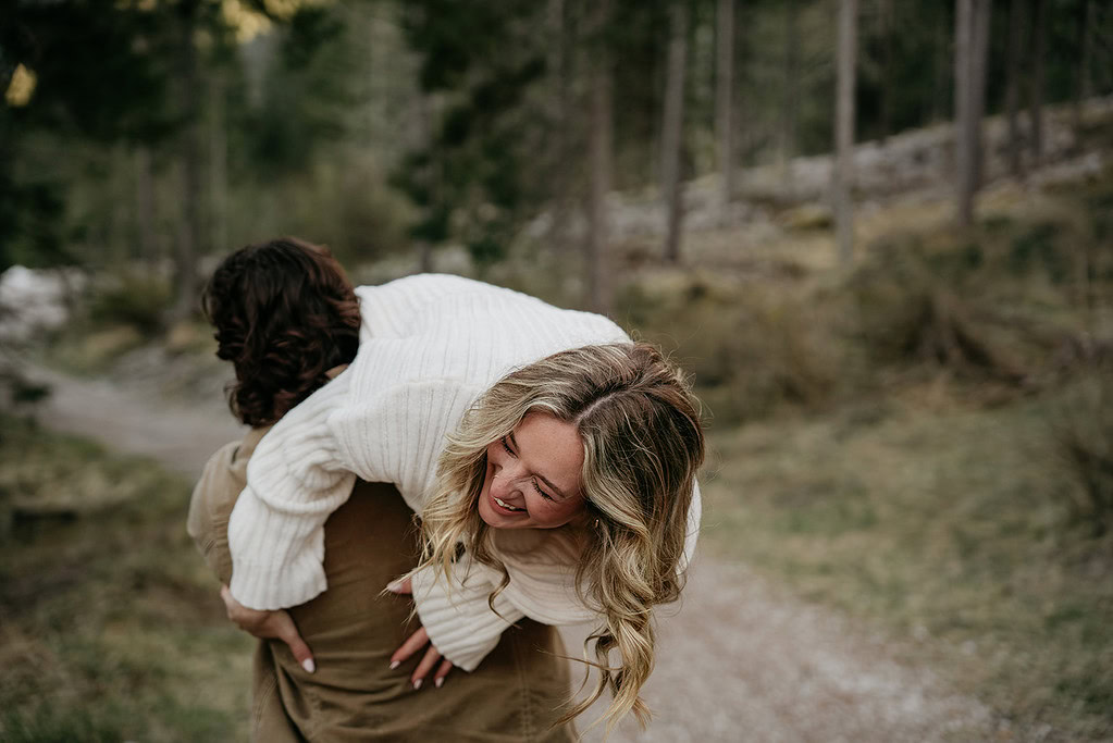 Laughing woman piggyback riding in forest