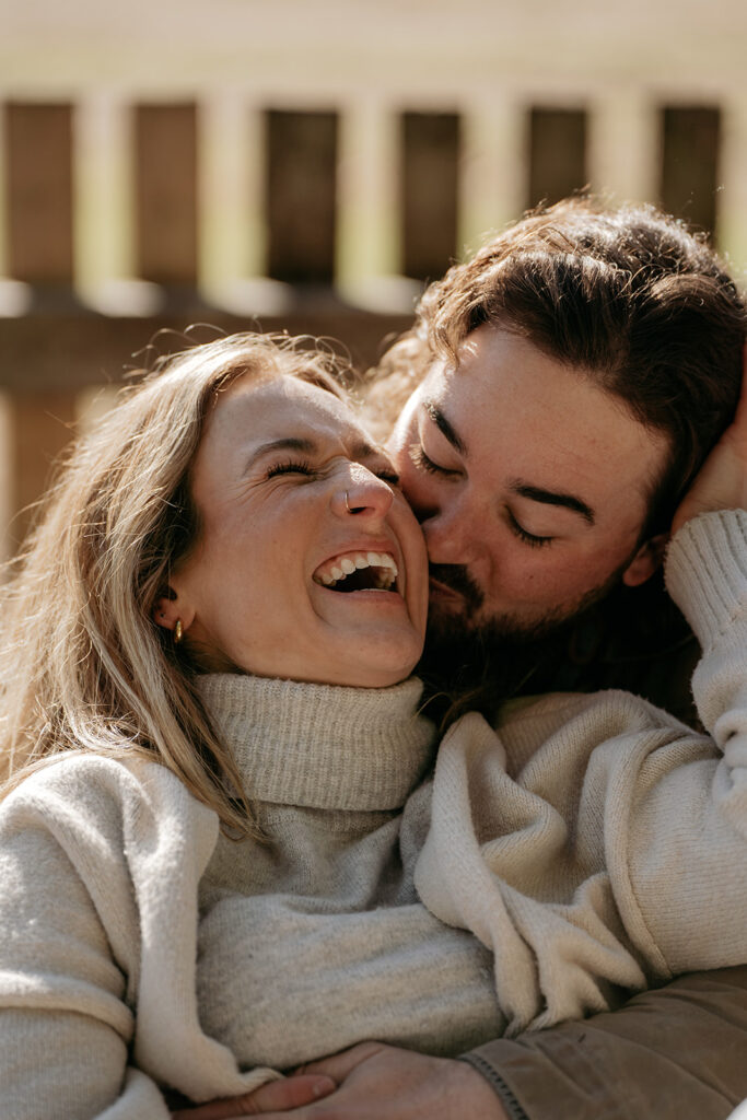 Couple laughing and embracing outdoors on a sunny day.