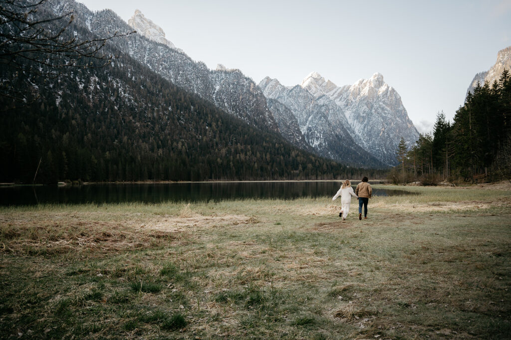 Couple running towards lake and mountains.