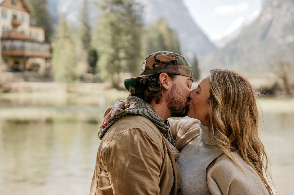 Couple kissing by a scenic lake.