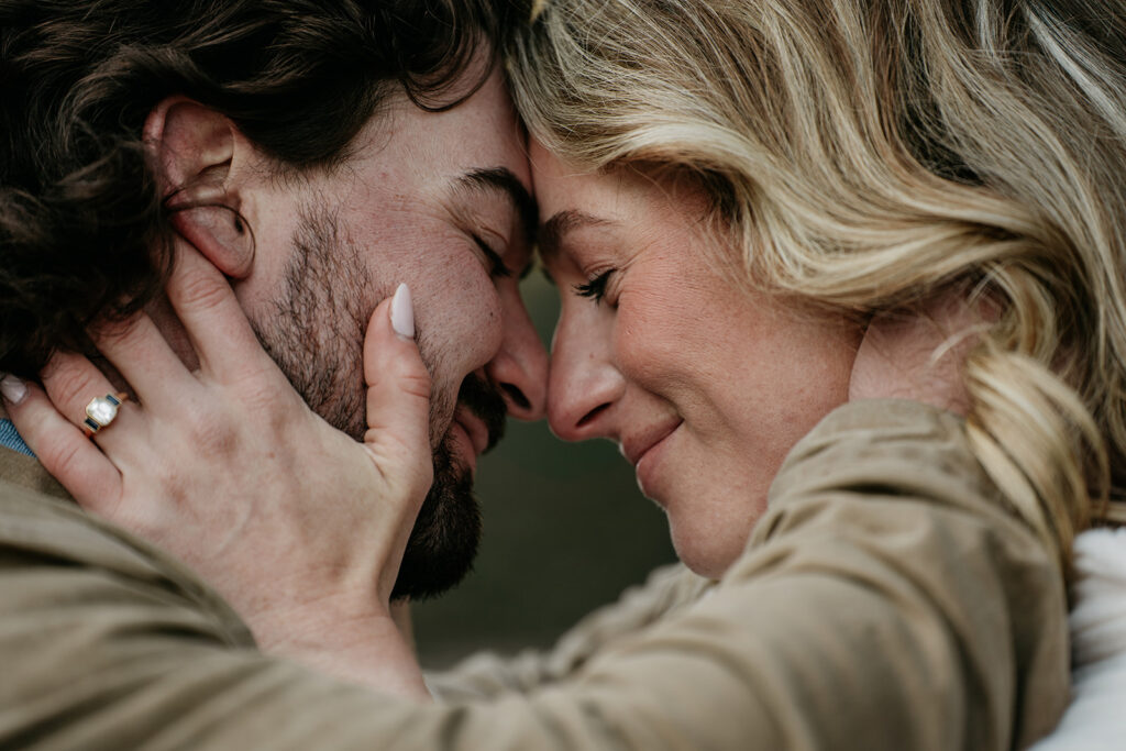 Couple embracing with heads together, smiling warmly.