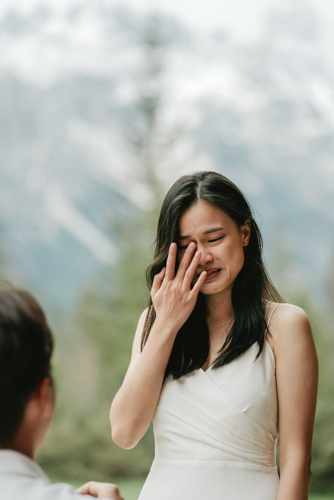 Emotional woman reacting to marriage proposal outdoors.