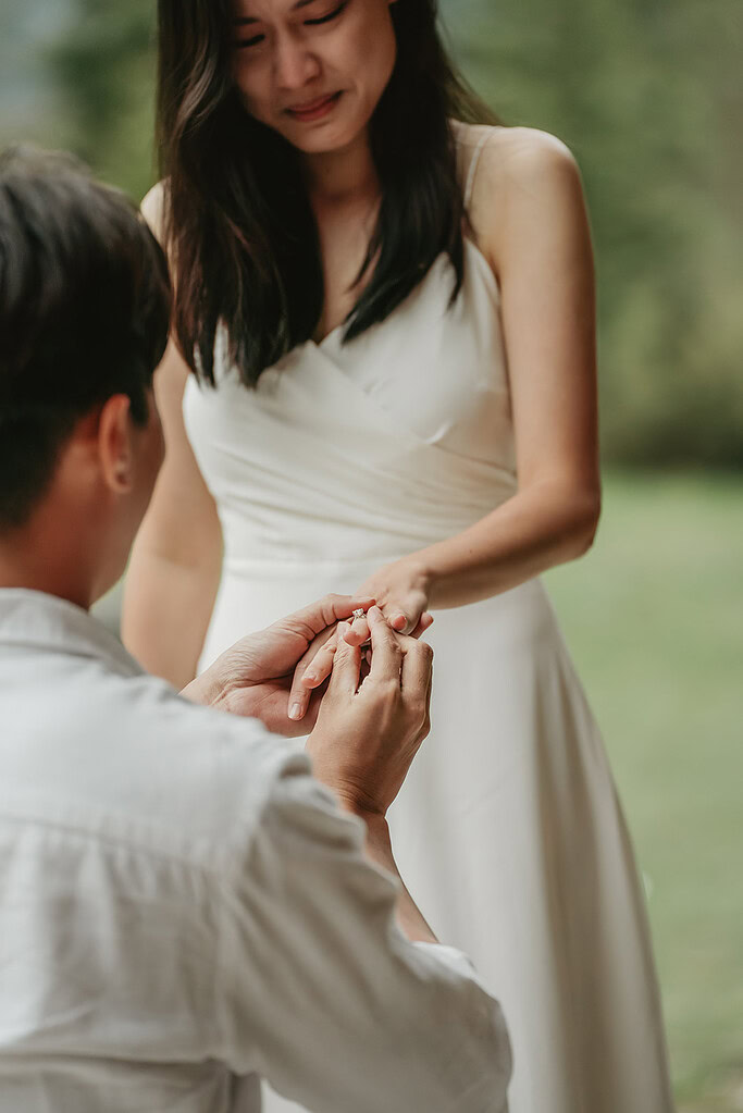 Man proposes, placing ring on woman's finger.