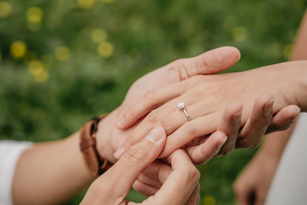 Person putting engagement ring on partner's finger