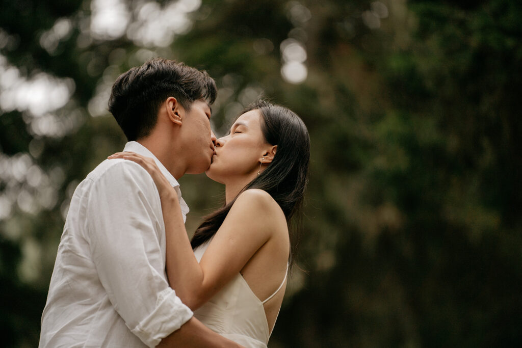 Couple kissing outdoors amidst nature.