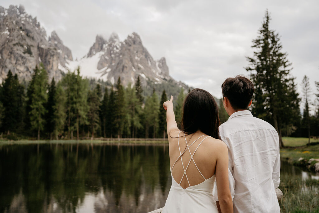 Couple pointing at mountain landscape over lake.