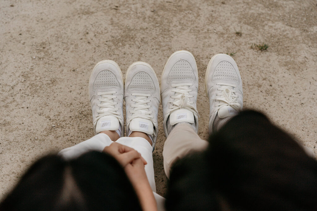 Two pairs of white sneakers on concrete