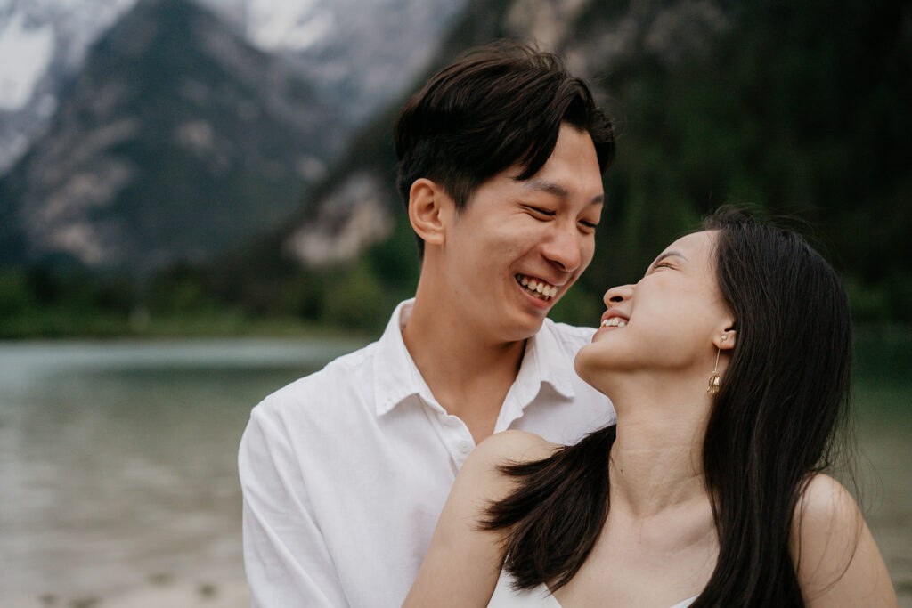 Couple smiling near a mountain lake.