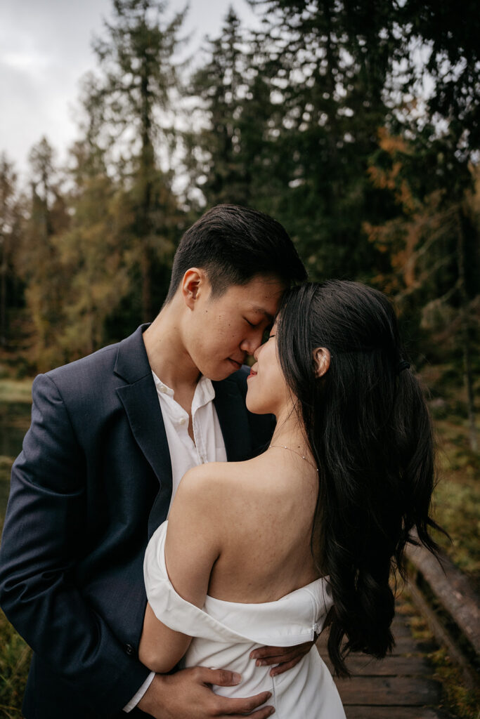 Couple embracing in a forest setting.