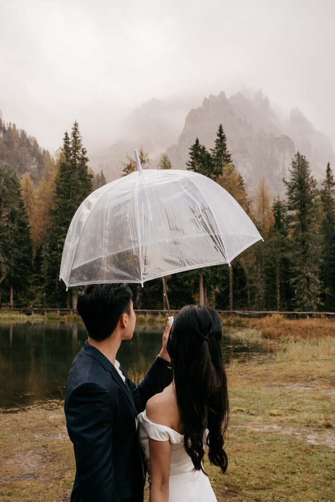 Couple with umbrella in scenic mountain landscape.