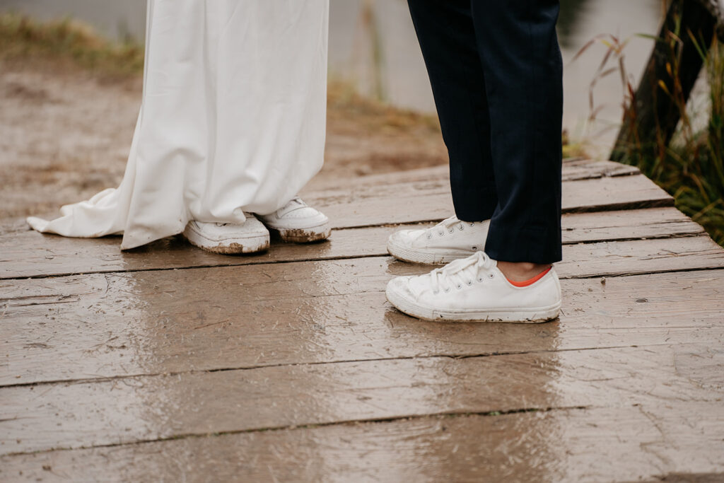 Bride and groom wearing muddy white sneakers outdoors.