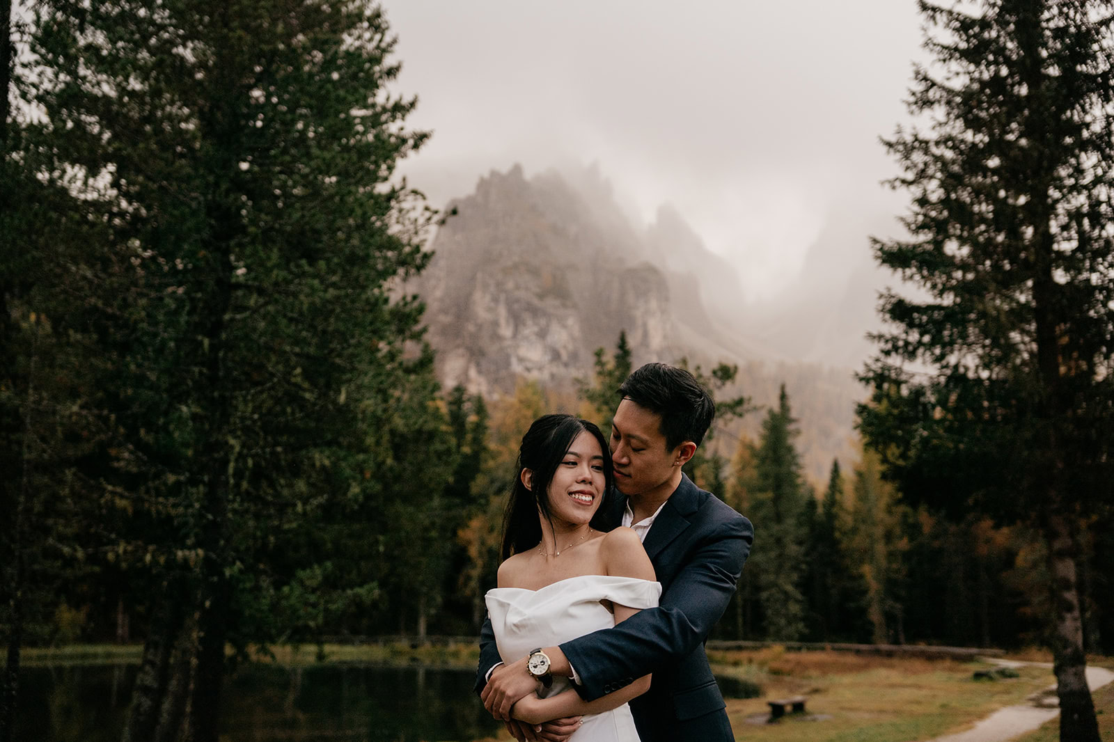 Couple embracing in scenic forest landscape.