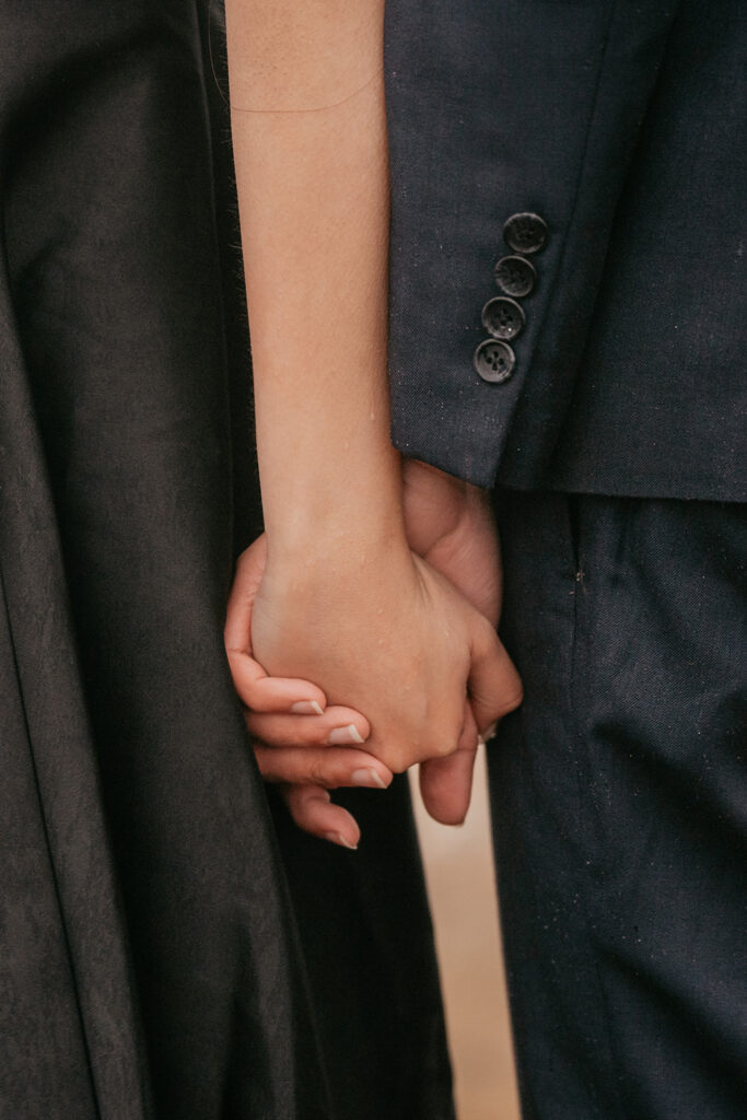 Couple holding hands in formal attire.