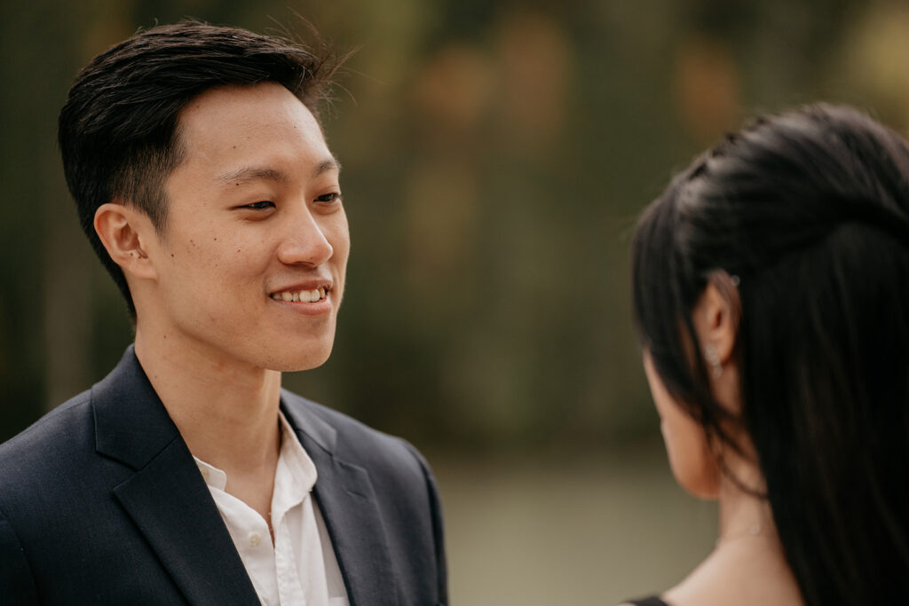 Couple smiling outdoors with blurred background.