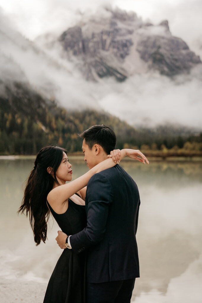 Couple embracing by misty mountain lake