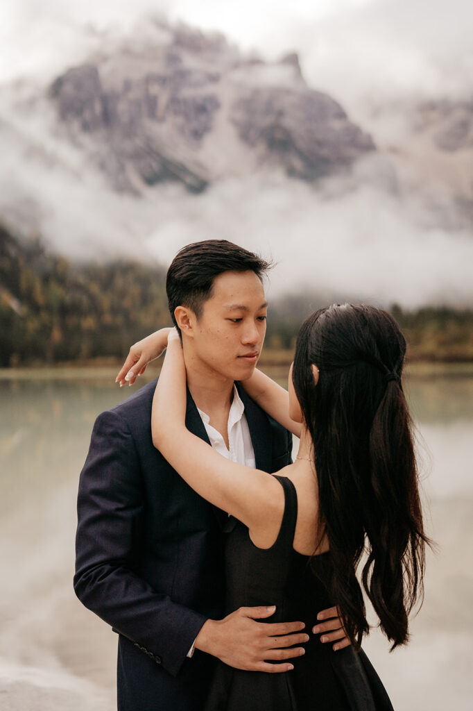 Couple embraces near misty mountain lake.