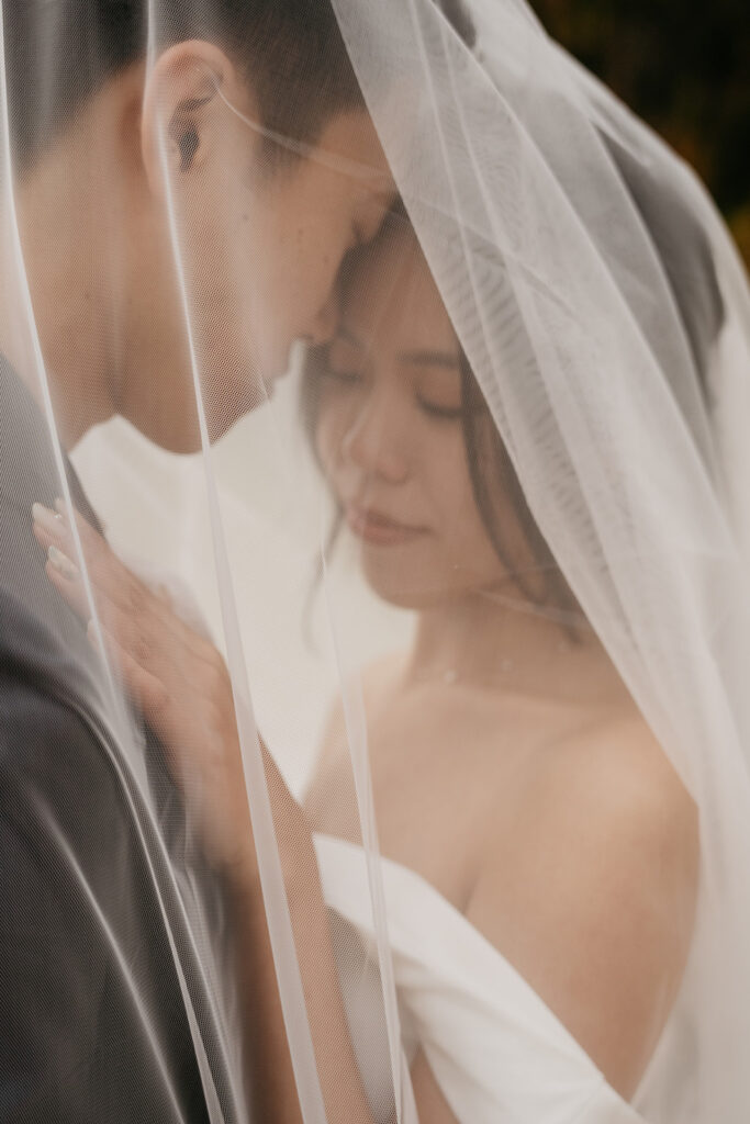 Bride and groom under wedding veil, intimate moment