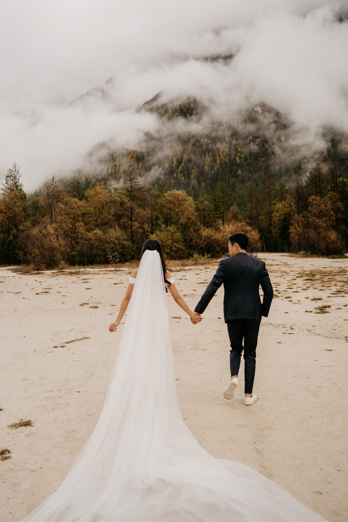 Wedding couple walking in misty forest.