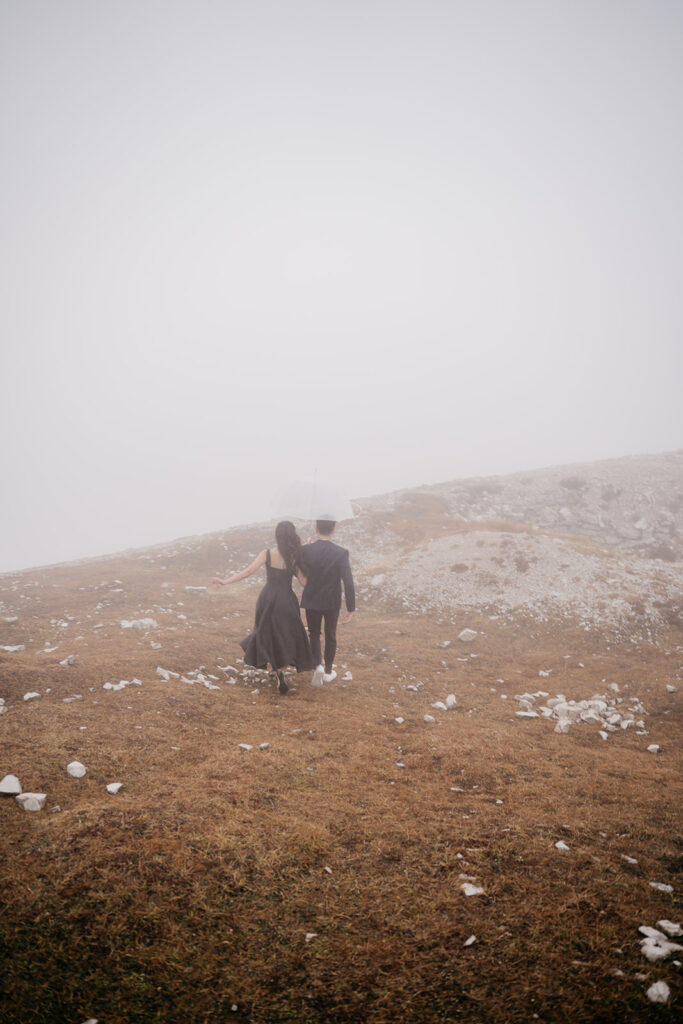 Couple walking with umbrella on misty hill