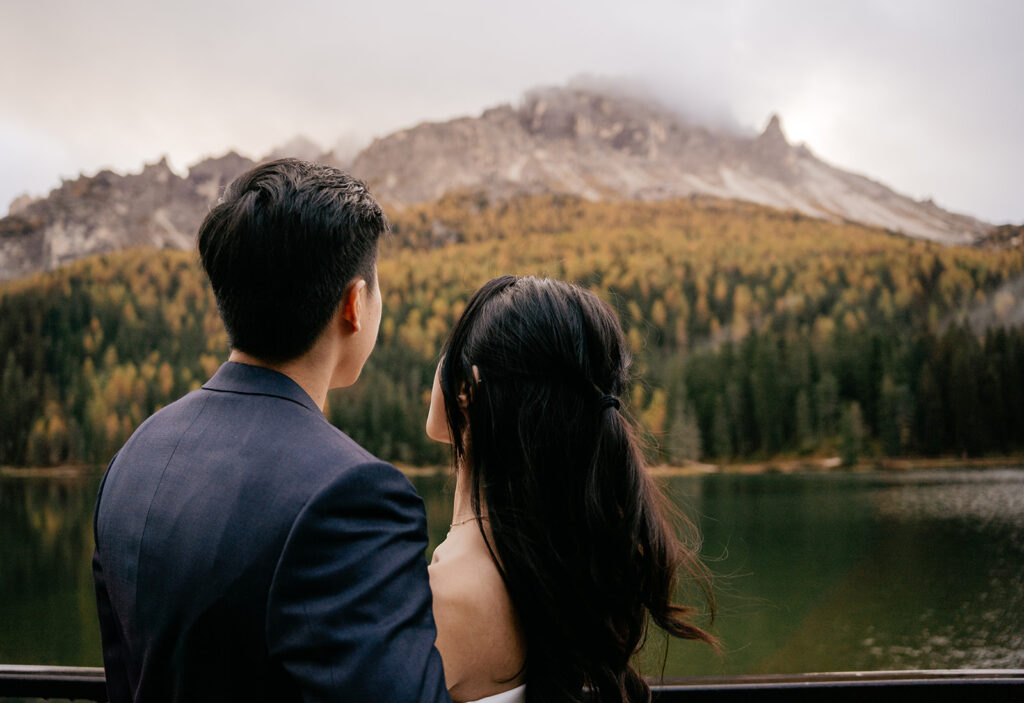 Couple admiring mountain view by lake.